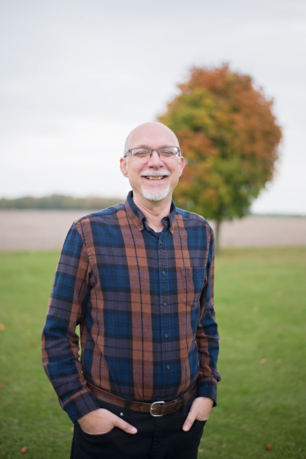 man with a plaid shirt and colourful tree in background