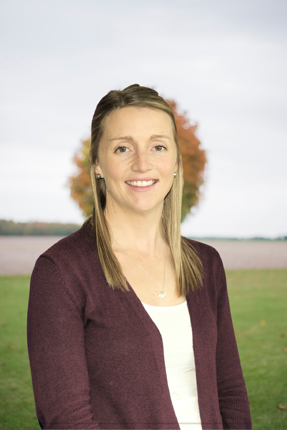 woman in a burgundy sweater with a colourful tree in background