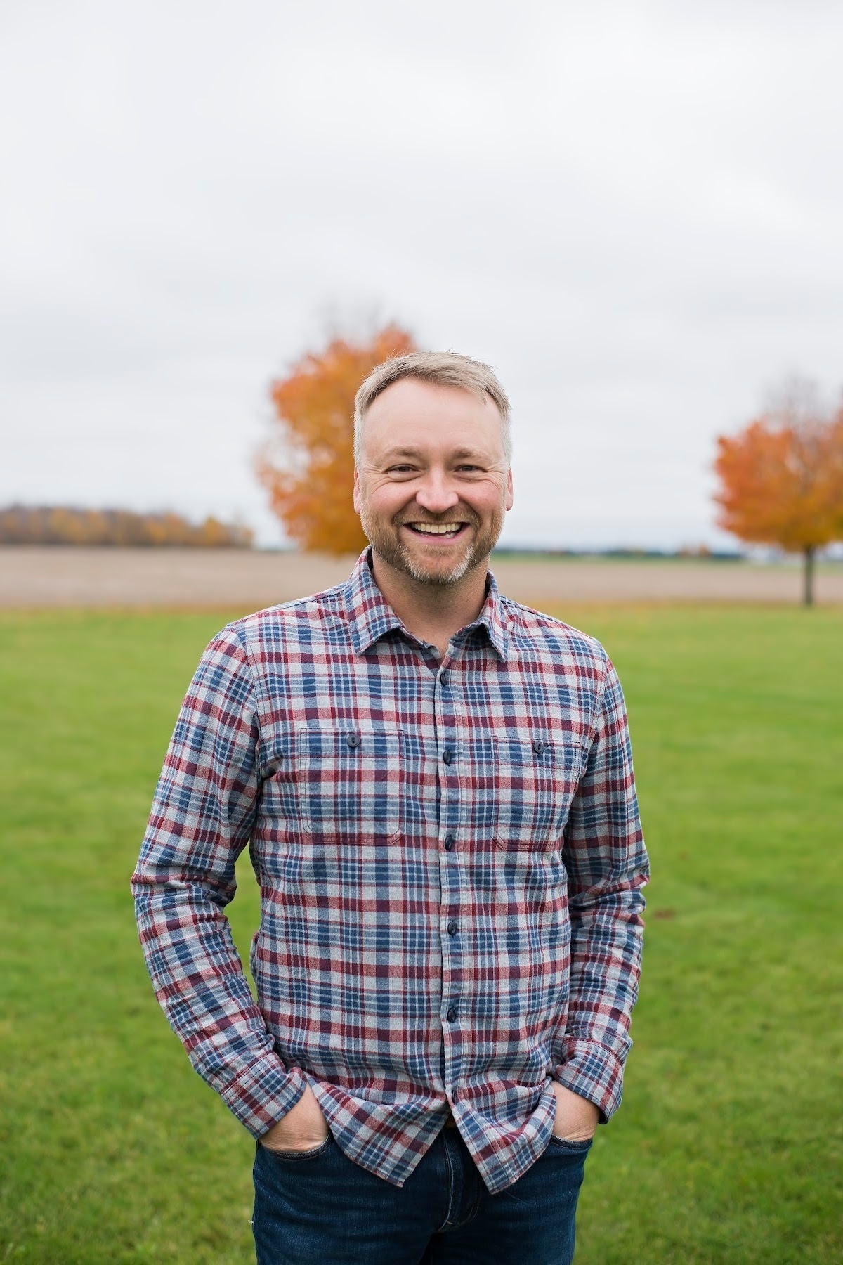 man with plaid shirt and colourful tree in background